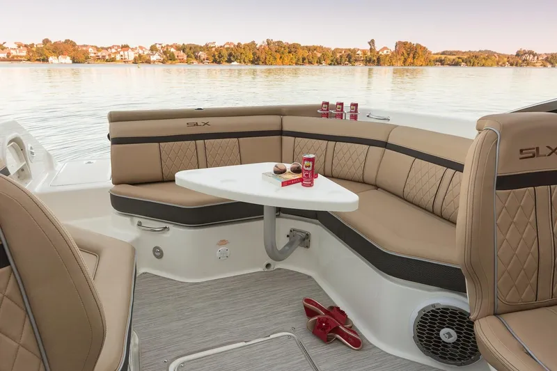 Slide: The Image of Manufacturer Provided Image: 2018 Sea Ray SLX 250 boat interior with tan seating and table on a calm lake. - 11