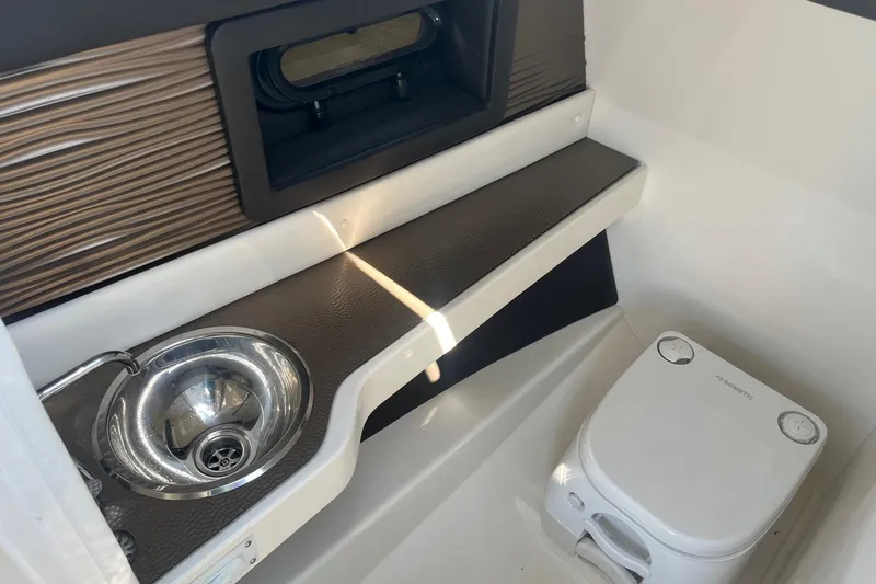 Slide: The Image of 2018 Sea Ray SLX 250 boat interior with sink and portable toilet. - 20