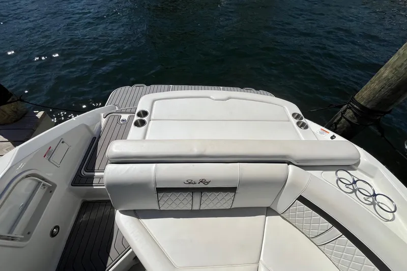 Slide: The Image of 2018 Sea Ray SLX 250 boat with white seating and cup holders, docked by the water. - 34
