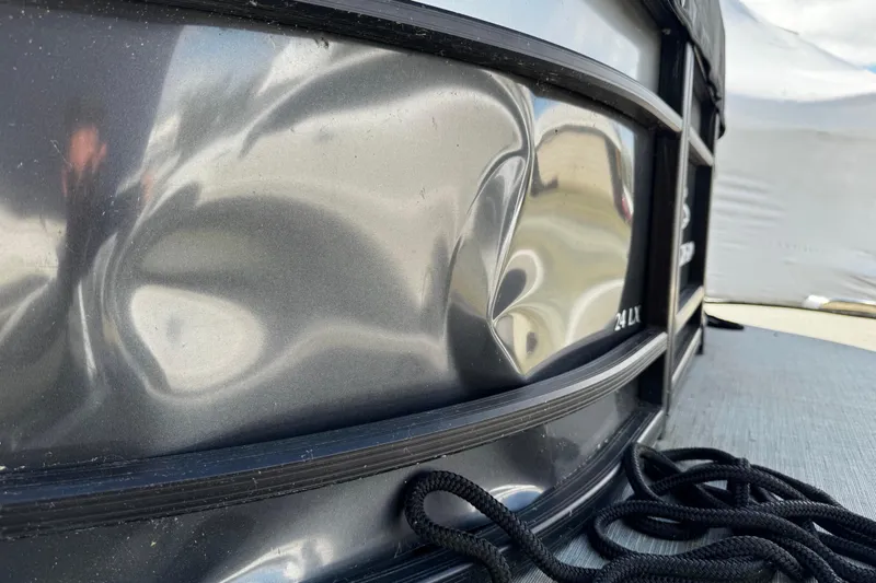 Slide: The Image of Close-up of a dented 2022 Bennington 24LX boat with black rope on the deck. - 13