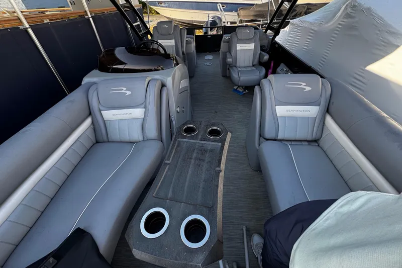 Slide: The Image of Interior of a 2022 Bennington 24LX pontoon boat with gray seating and cup holders. - 3