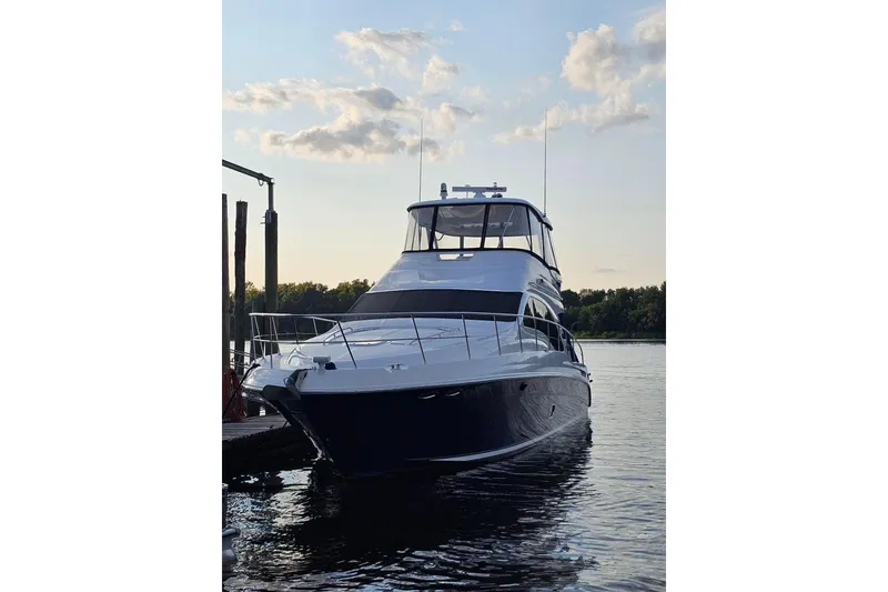 Slide: The Image of 2007 Sea Ray 580 Sedan Bridge yacht docked at sunset, reflecting on calm water. - 2