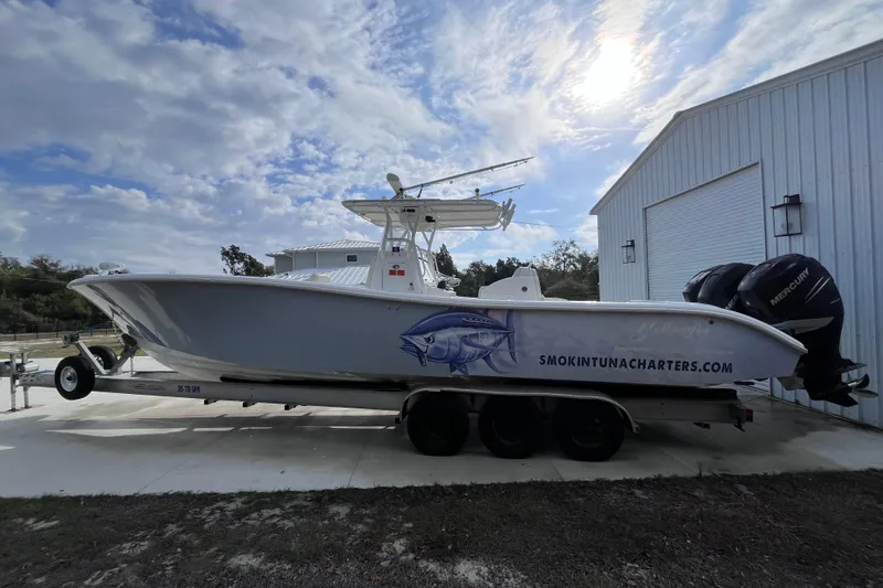 Slide: The Image of 2004 Yellowfin 36 Offshore boat on trailer, parked beside a white building under a cloudy sky. - 5