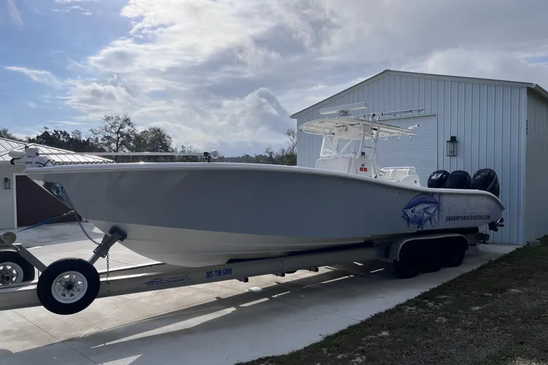 Slide: The Image of 2004 Yellowfin 36 Offshore boat on trailer, parked beside a white building. - 6
