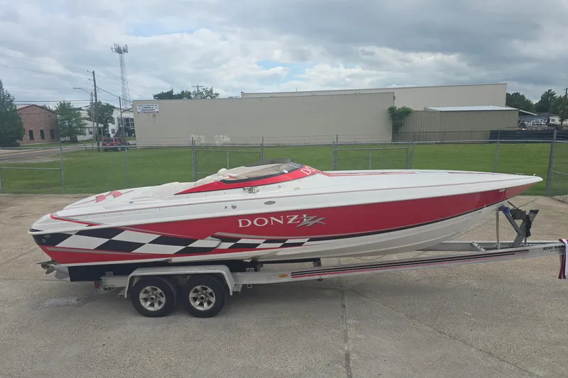 The Image of 1999 Donzi 28 ZX speedboat on trailer, red and white design, parked outdoors. - 0