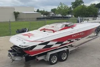 Slide: The Image of 1999 Donzi 28 ZX boat on trailer in a parking lot, surrounded by buildings and vehicles. - 3