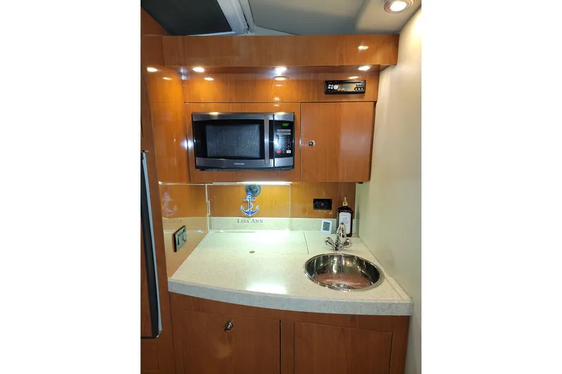 Slide: The Image of 2007 Regal Commodore 3760 IB yacht kitchenette with microwave, sink, and wooden cabinetry. - 2