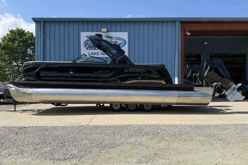 The Image of 2026 Godfrey Sanpan 2700 ULW Twin pontoon boat displayed outside a marine dealership. - 2
