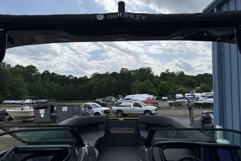 Slide: The Image of 2026 Godfrey Sanpan 2700 ULW Twin pontoon boat at marina with parked vehicles. - 45