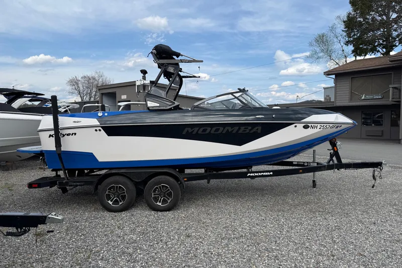 The Image of 2021 Moomba Kaiyen boat on trailer, blue and white design, parked outdoors. - 0