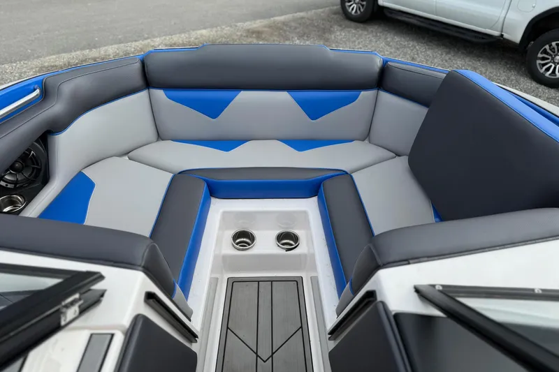 Slide: The Image of 2021 Moomba Kaiyen boat interior with blue and gray seating, cup holders, and speaker. - 14
