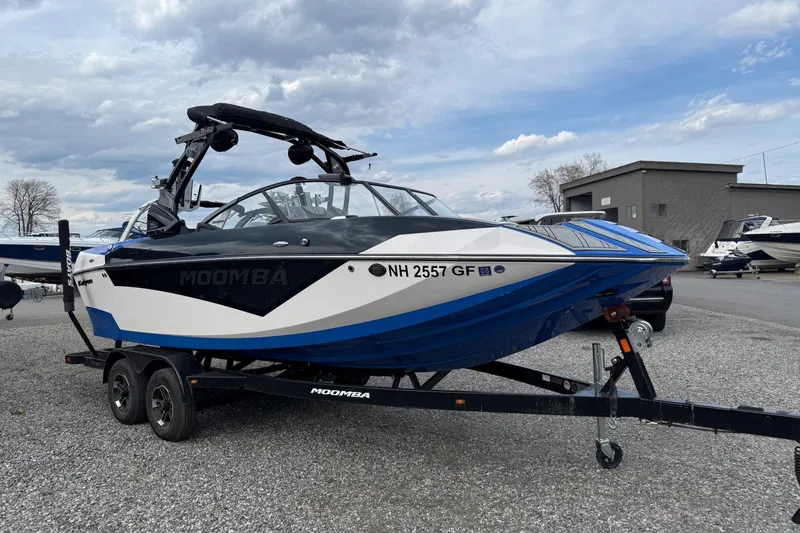 Slide: The Image of 2021 Moomba Kaiyen boat on trailer, blue and white design, parked outdoors. - 2