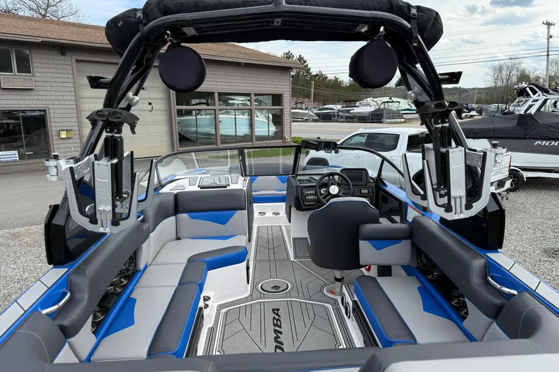Slide: The Image of 2021 Moomba Kaiyen boat interior with blue and gray seating, advanced dashboard, and wakeboard racks. - 9