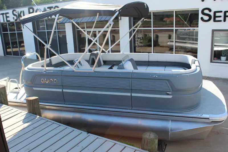 Slide: The Image of 2026 Tahoe Pontoon Aura boat with canopy, docked outside a service center. - 12