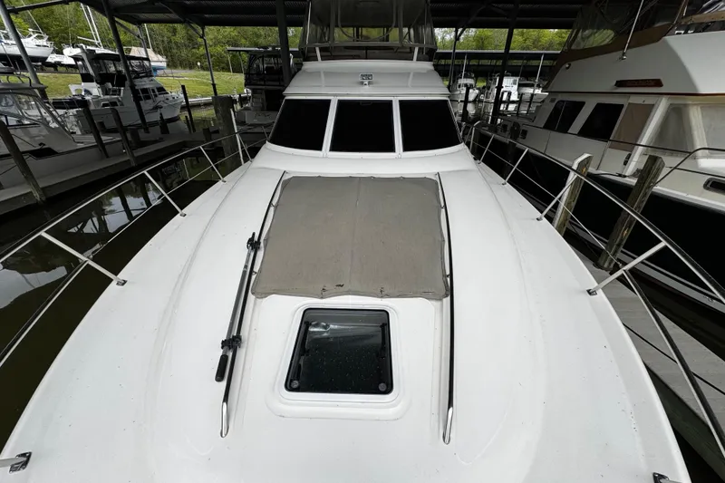 Slide: The Image of 1999 Sea Ray 480 Sedan Bridge yacht docked, showcasing sleek design and spacious deck. - 13