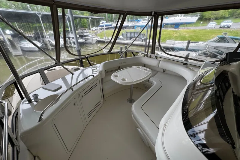 Slide: The Image of 1999 Sea Ray 480 Sedan Bridge interior with seating and table, docked at marina. - 19