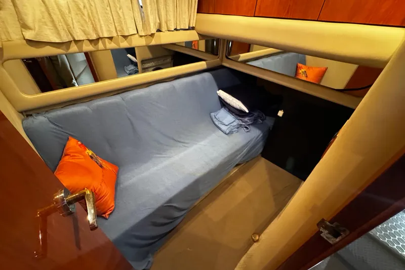 Slide: The Image of Interior cabin of 1999 Sea Ray 480 Sedan Bridge with blue bedding and orange pillows. - 27