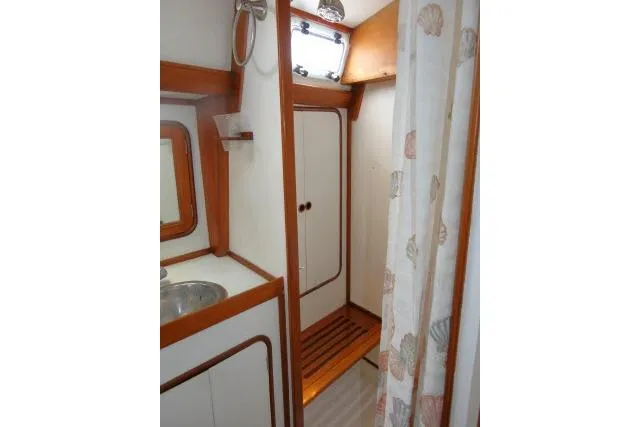 Slide: The Image of Bathroom interior of 1986 Tayana 52 Center Cockpit yacht with wood accents and shower curtain. - 23