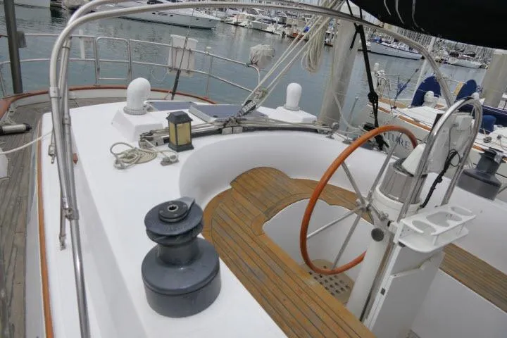 Slide: The Image of 1986 Tayana 52 Center Cockpit sailboat with wooden deck and steering wheel, docked at marina. - 32