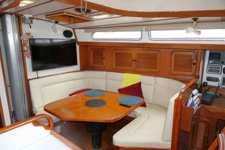 Slide: The Image of 1986 Tayana 52 Center Cockpit interior with cozy seating, wooden table, and modern amenities. - 5