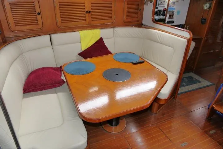 Slide: The Image of Cozy dining area in 1986 Tayana 52 Center Cockpit yacht with wooden table and cushioned seating. - 6