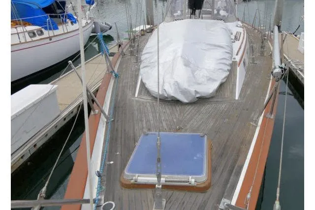 Slide: The Image of 1986 Tayana 52 Center Cockpit sailboat docked, featuring a covered deck and wooden finish. - 60