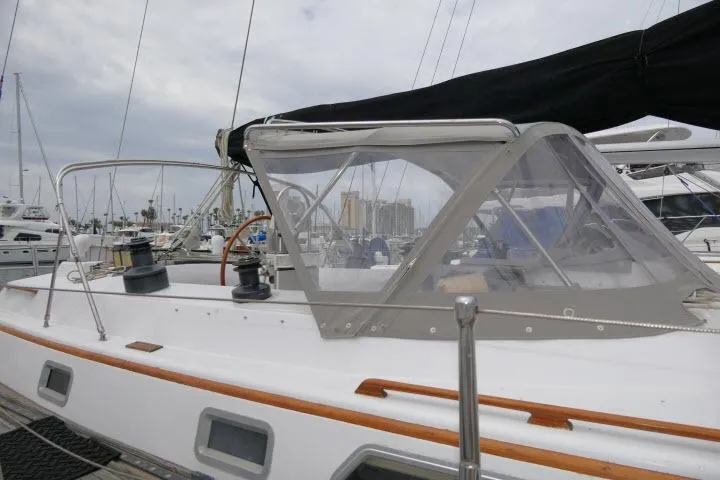 Slide: The Image of 1986 Tayana 52 Center Cockpit sailboat docked, featuring a sleek design and protective cockpit cover. - 62