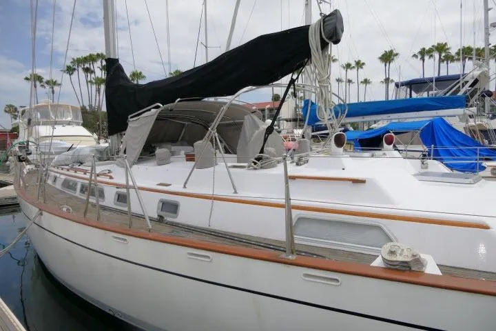 Slide: The Image of 1986 Tayana 52 Center Cockpit sailboat docked at marina with palm trees in background. - 65