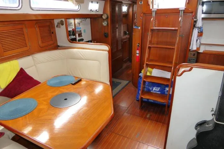 Slide: The Image of Interior of 1986 Tayana 52 Center Cockpit yacht with wooden dining area and ladder. - 7