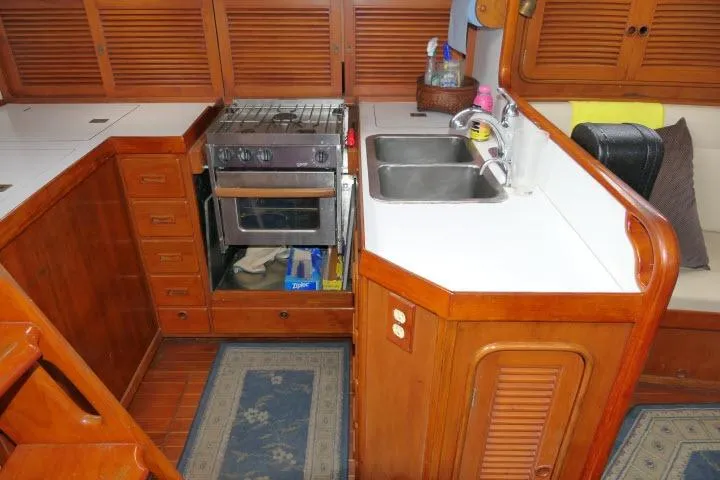 Slide: The Image of Interior of 1986 Tayana 52 Center Cockpit yacht kitchen with stove, sink, and wooden cabinetry. - 8