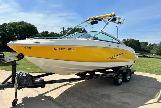 Slide: The Image of 2006 Chaparral 236 SSi boat with yellow hull on a trailer, parked outdoors. - 2