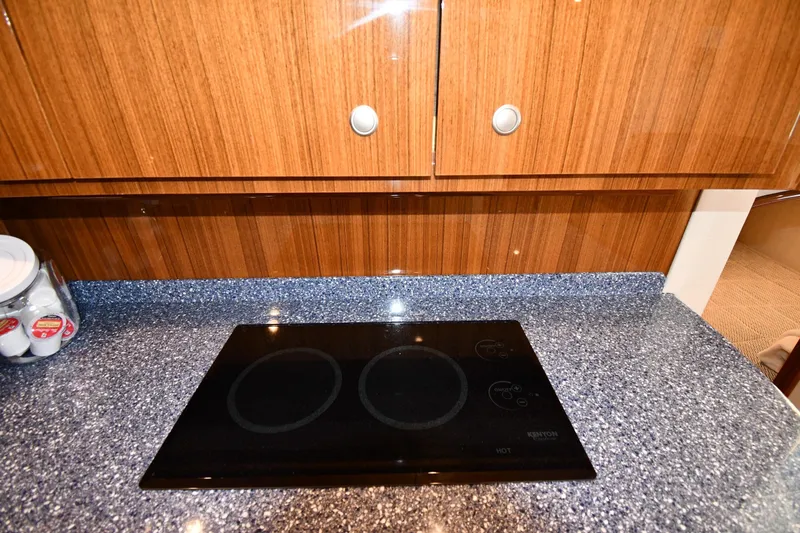 Slide: The Image of Modern kitchen area in 2012 Viking 42 Open yacht with sleek cooktop and wooden cabinetry. - 52