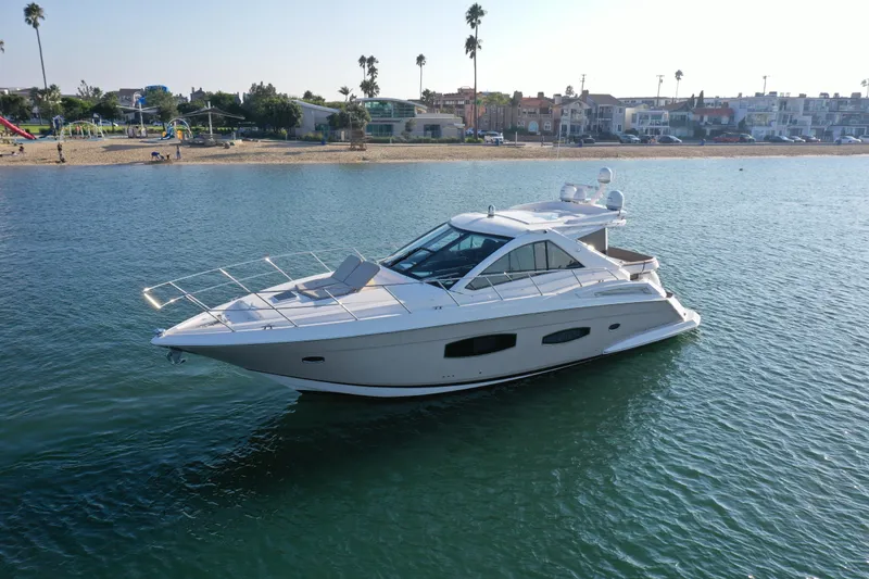 Slide: The Image of 2015 Regal 53 Sport Coupe yacht cruising near a sandy beach with palm trees. - 3