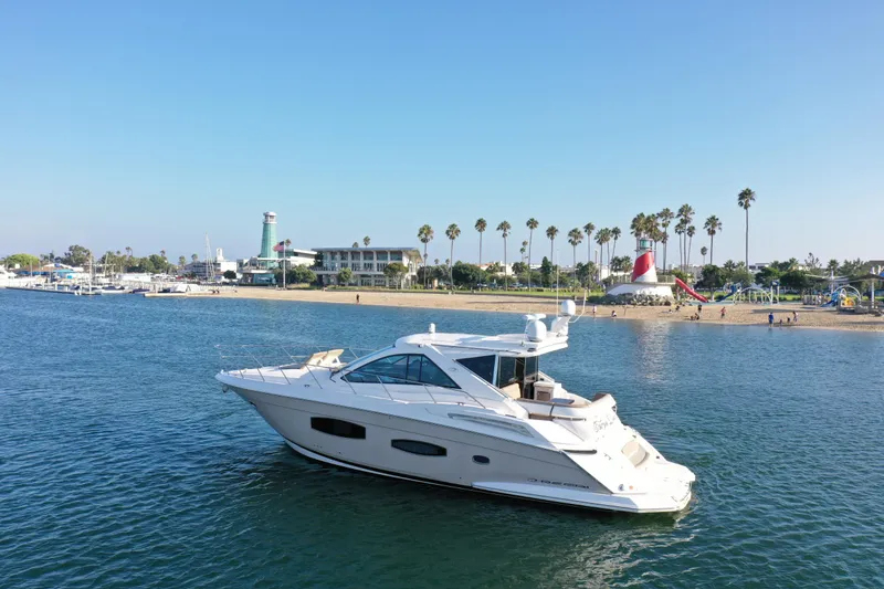 Slide: The Image of 2015 Regal 53 Sport Coupe yacht cruising near a scenic beach with lighthouse and palm trees. - 5