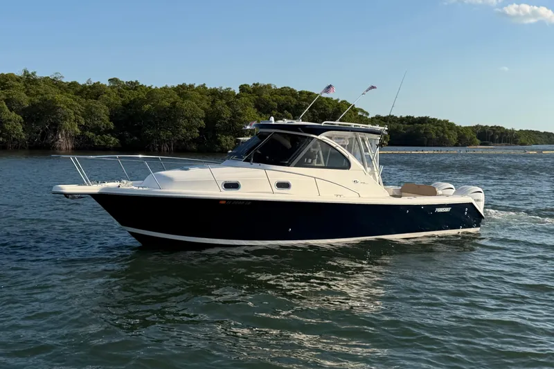 The Image of 2009 Pursuit OS 315 Offshore boat cruising on a calm lake with lush greenery. - 1