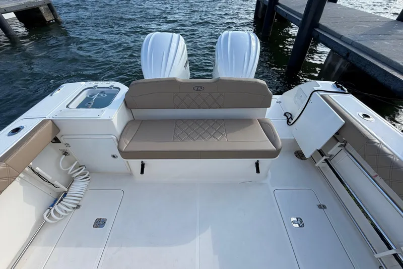 Slide: The Image of 2009 Pursuit OS 315 Offshore boat interior with seating and twin engines at dock. - 12