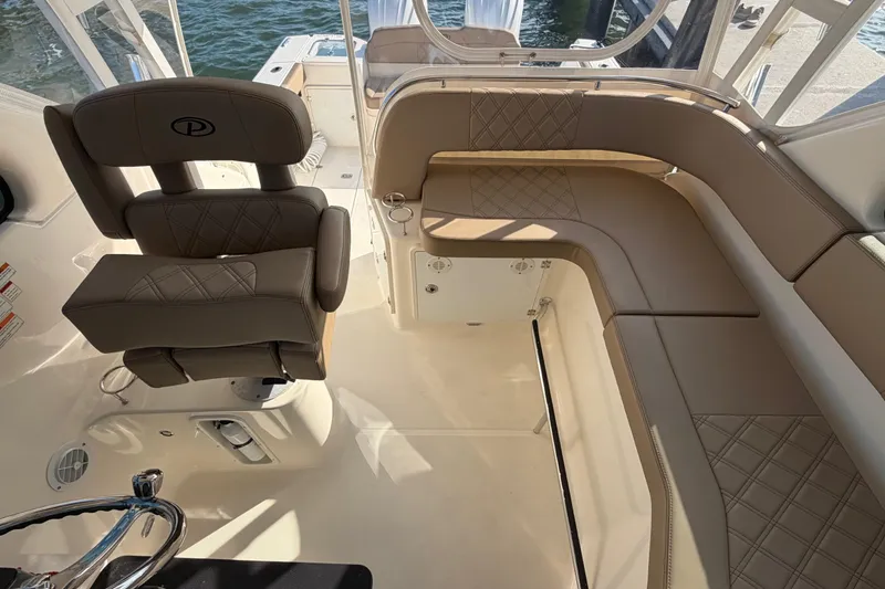 Slide: The Image of 2009 Pursuit OS 315 Offshore boat interior with beige seating and steering wheel. - 24