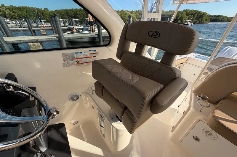 Slide: The Image of 2009 Pursuit OS 315 Offshore boat interior with helm seat and steering wheel, dockside view. - 26