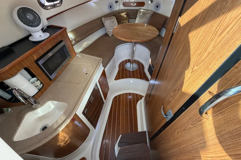 Slide: The Image of 2009 Pursuit OS 315 Offshore cabin interior with kitchenette, seating, and wooden finishes. - 28
