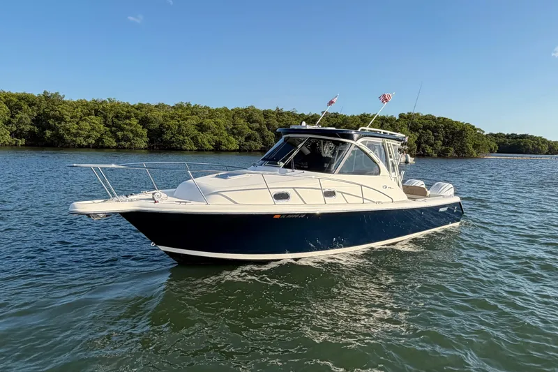 Slide: The Image of 2009 Pursuit OS 315 Offshore boat on calm water with lush green shoreline. - 3