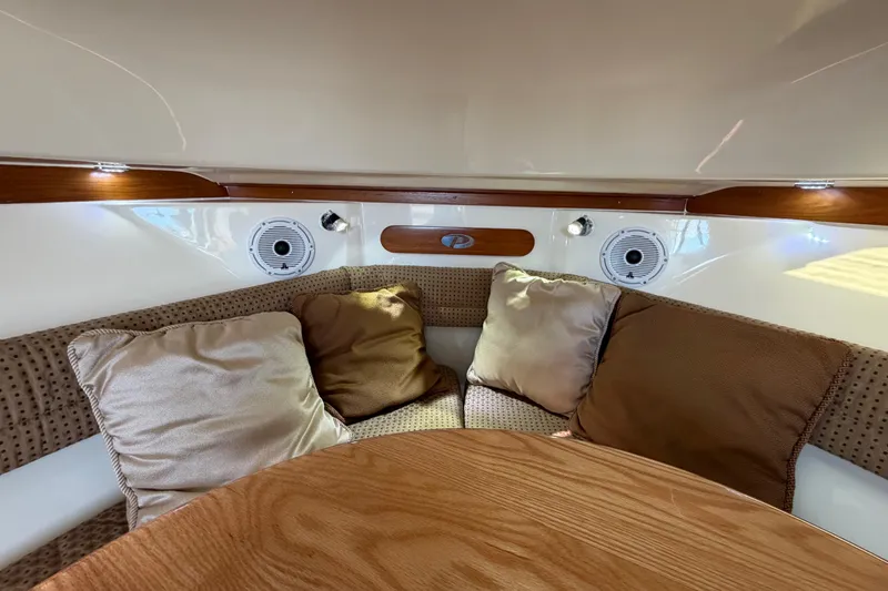 Slide: The Image of 2009 Pursuit OS 315 Offshore cabin interior with plush cushions and wooden accents. - 32