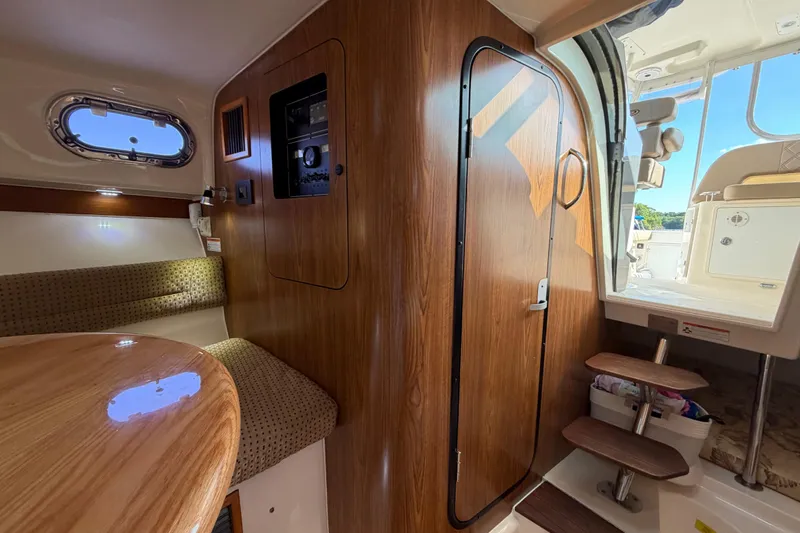Slide: The Image of Interior of a 2009 Pursuit OS 315 Offshore boat, featuring wood paneling and seating. - 33