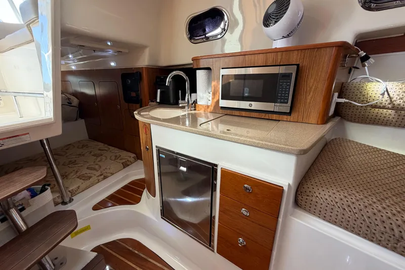 Slide: The Image of 2009 Pursuit OS 315 Offshore cabin interior with kitchenette, microwave, and seating area. - 34
