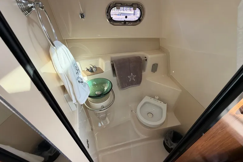 Slide: The Image of 2009 Pursuit OS 315 Offshore boat bathroom with sink, toilet, and porthole window. - 37