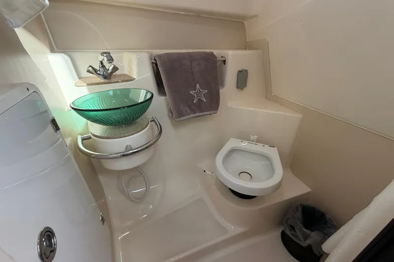 Slide: The Image of 2009 Pursuit OS 315 Offshore bathroom with glass sink, towel, and compact toilet. - 38