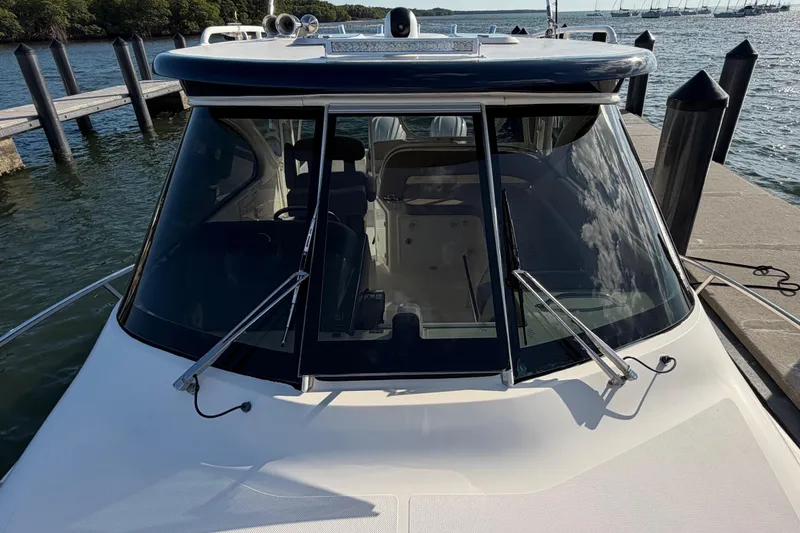 Slide: The Image of 2009 Pursuit OS 315 Offshore boat docked, showcasing sleek windshield design and wipers. - 44