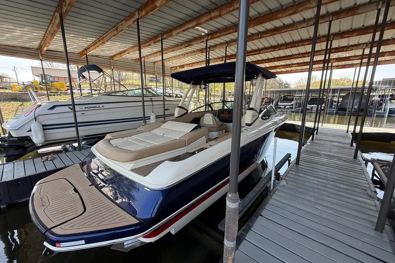 Slide: The Image of 2026 Chris-Craft Sportster 28 docked in a covered marina, showcasing sleek design and luxury features. - 13