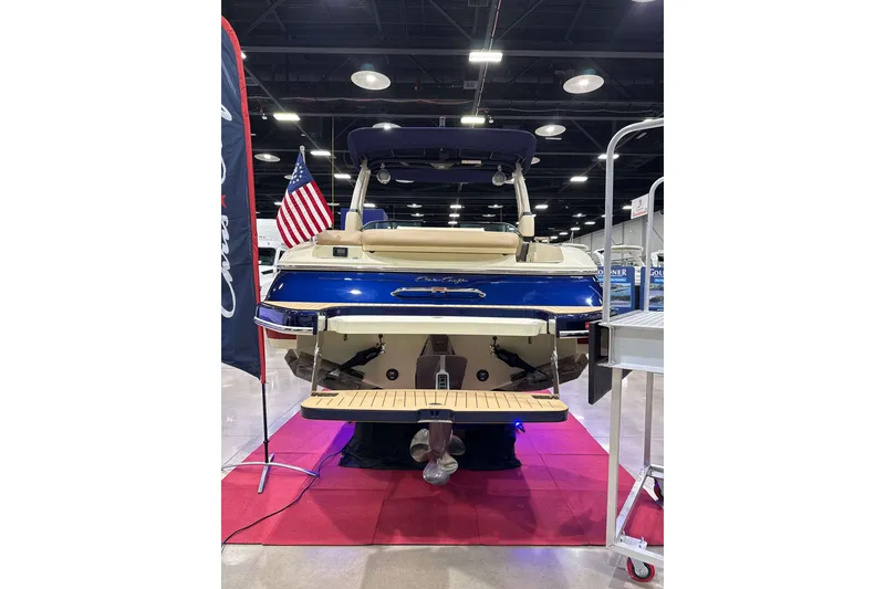Slide: The Image of 2026 Chris-Craft Sportster 28 boat displayed indoors with American flag. - 3