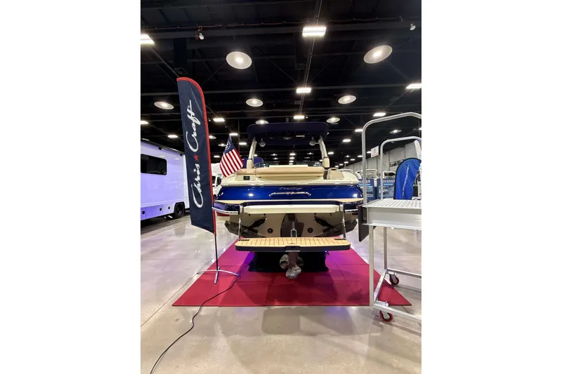Slide: The Image of 2026 Chris-Craft Sportster 28 boat displayed indoors with American flag and branding. - 5