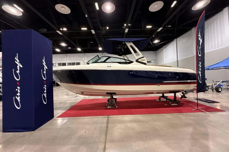 Slide: The Image of 2026 Chris-Craft Sportster 28 boat displayed indoors on a red carpet. - 7